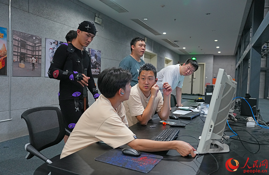 崔晟輯（前排右二）和團(tuán)隊(duì)成員在動作捕捉棚內(nèi)討論設(shè)計(jì)方案。 人民網(wǎng)記者 崔新耀攝